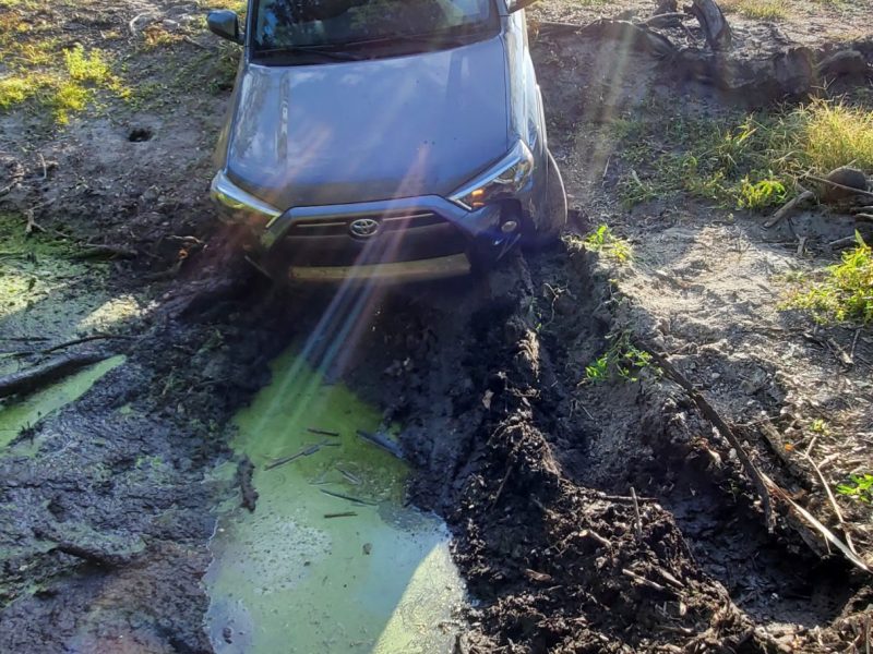 Toyota car stuck in the mud and pulled by the tow truck